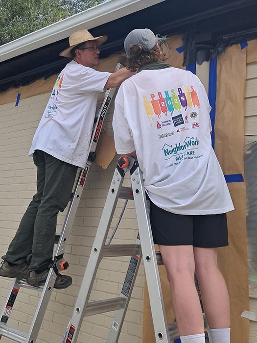 Two men on ladders painting a house