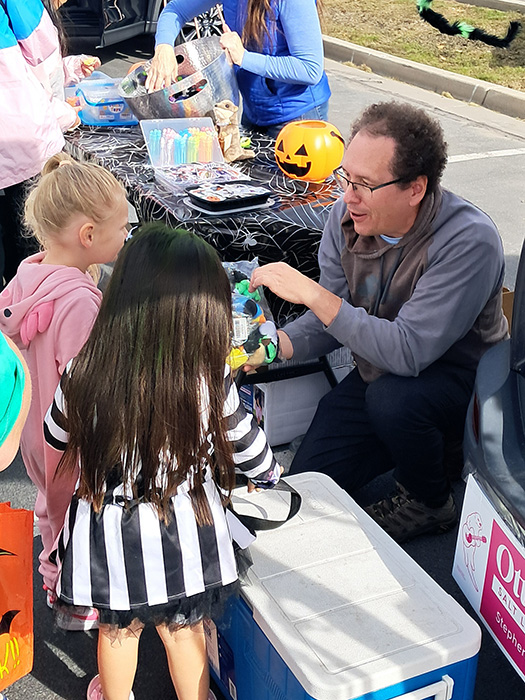 Man crouching down and giving candy to trick-or-treaters