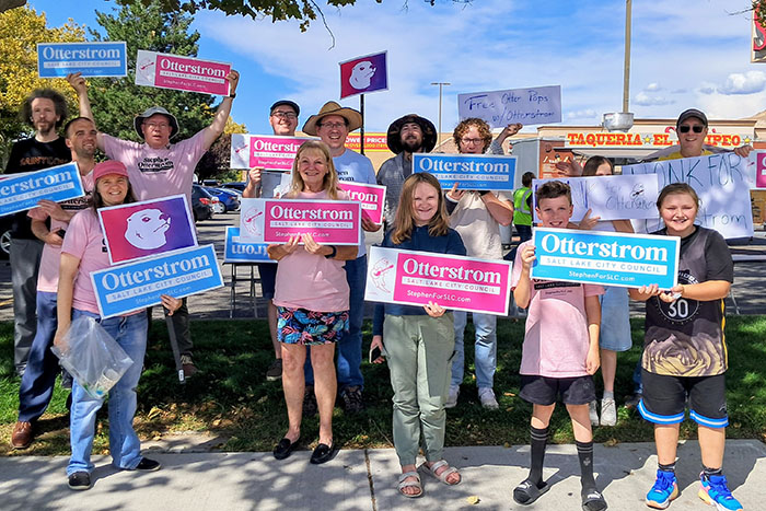 Group of people wearing pink shirts and holding blue and pink campaign signs