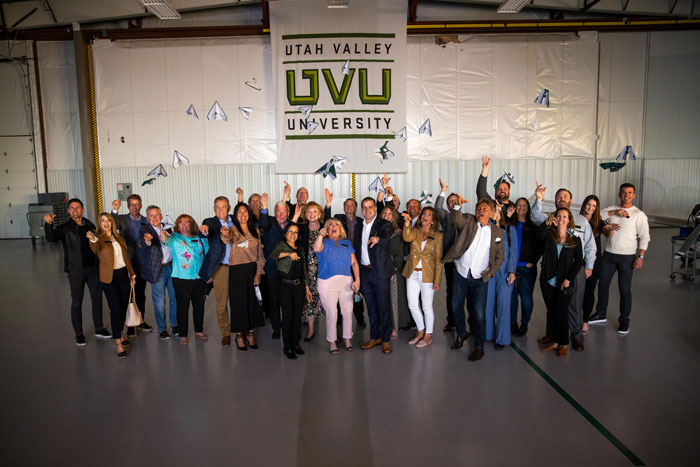 A group of people standing together with their arms up after throwing paper airplanes.