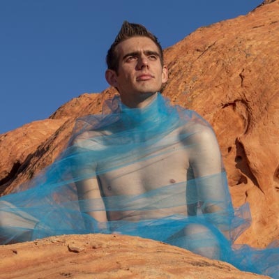 Man sitting on an orange mountain with a cyan shroud