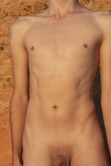 A nude man standing against a mountain