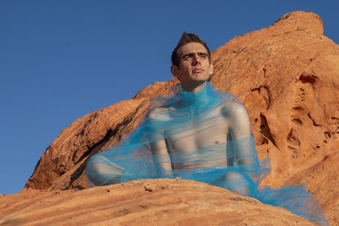 Man sitting on an orange mountain with a cyan shroud