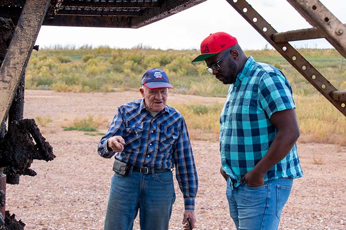 Two men standing next to an oil rig