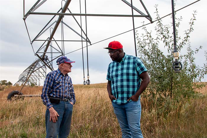 Two standing in a field in front of equipment