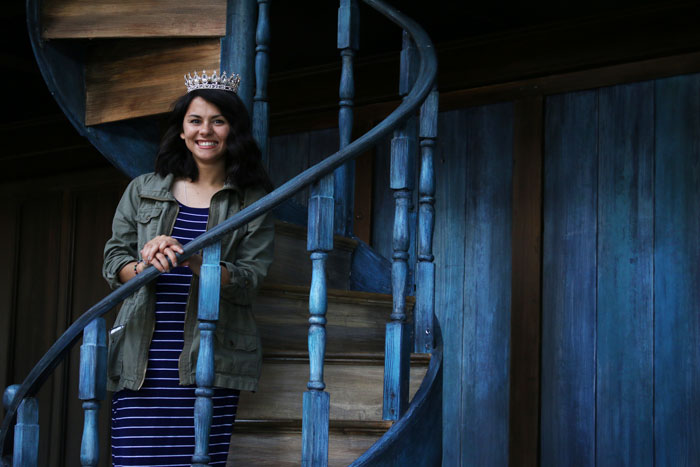 A homecoming queen wearing a tiara standing on a staircase